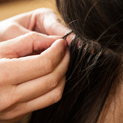 Close up of a woman with brunette hair receiving hair extensions.