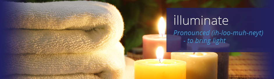Neatly folded towels on a table with warm colored, lit candles in an outdoor environment.