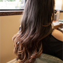 Lady with long, wavy, brunette hair sitting in a chair.